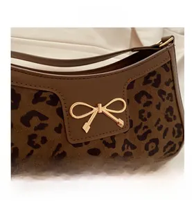Detail shot of leopard print underarm bag with gold bow clasp and brown leather trim