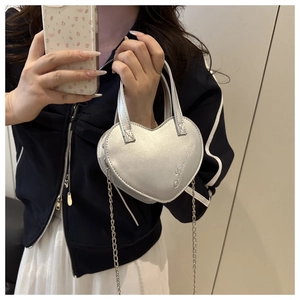 Détail du sac bandoulière argenté en forme de cœur avec broderie et chaîne en métal