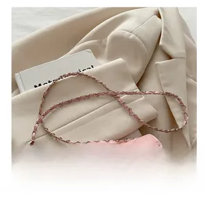 Détail d'un mini sac bandoulière matelassé rose avec chaîne argentée sur une veste