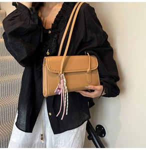 Close-up of light brown PU leather shoulder bag with colorful fringe cartoon charm detail
