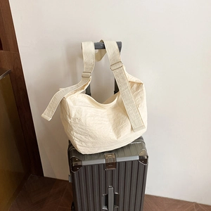 Minimalist creamy white crescent crossbody bag with pleated texture and adjustable wide strap