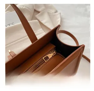 Close-up of smooth golden metal zipper on brown leather tote bag with neat stitching