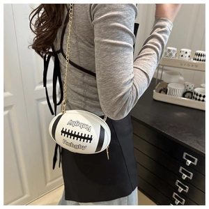 Detail der Rugby-förmigen Umhängetasche mit goldener Kette auf Lifestyle-Hintergrund