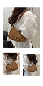 Detail of a brown crescent bag featuring a textured fabric and a gold bow buckle