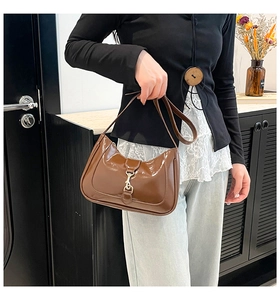 Close-up of brown patent leather Jackie bag with gold clasp and glossy vintage texture