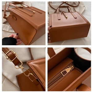 Detail view of brown leather tote showing gold zippers, stitching and adjustable strap