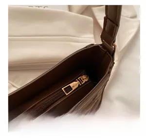 Close-up of smooth gold metal zipper and leopard print texture on brown shoulder bag