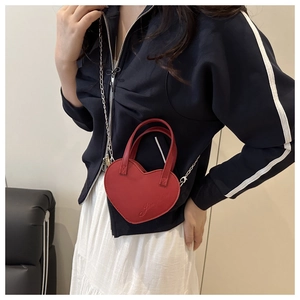 Mannequin portant un sac bandoulière coeur rouge en cuir avec chaîne métallique