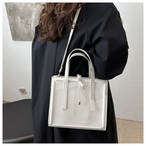 Minimalist white structured handbag with decorative knot detail and gold hardware