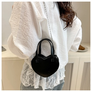Vue de dos d'un mannequin portant un mini sac cœur noir avec une fine chaîne en argent