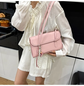 Pink faux leather shoulder bag featuring decorative fringe tassel in modern kitchen setting