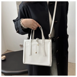 Detail of white leather handbag showing vertical stitching and drawstring metal charm detail