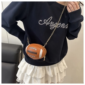Detail of brown rugby-shaped crossbody bag featuring white stripes and golden chain strap