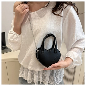 Détail du sac à main noir en forme de cœur avec bandoulière chaîne et poignée