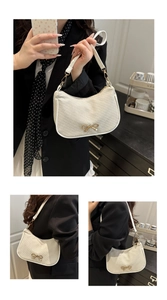Detail of cream shoulder bag with golden bow hardware and fine twill texture