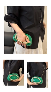 Detail of bright green high-gloss oval clutch with golden C-shaped handle and chain