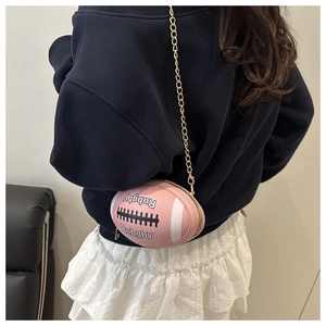 Pink rugby-shaped mini shoulder bag with gold chain strap shown on model's shoulder