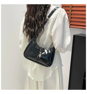 Detail view of glossy black lacquer leather hobo bag with vintage gold metal buckle
