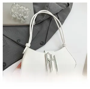 Détail de la boucle métallique argentée et du nœud sur un sac à bandoulière blanc chic