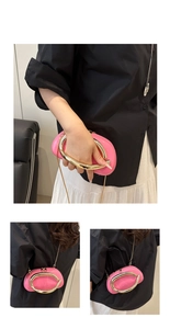 Close-up of shiny pink oval handbag with gold metal handle and chain shoulder strap