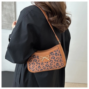 Close-up of brown leopard print underarm bag with gold bow buckle and shoulder strap