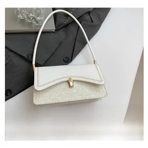 Detailed view of white crossbody bag with sequin panel and golden turn-lock closure