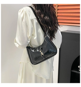 Detail of black patent leather hobo bag with distinctive piston clasp and shoulder strap