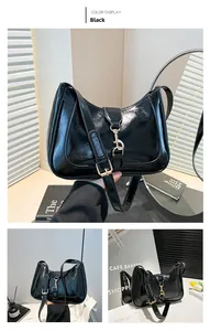 Detailed close-up of glossy black patent leather crescent bag with gold buckle hardware