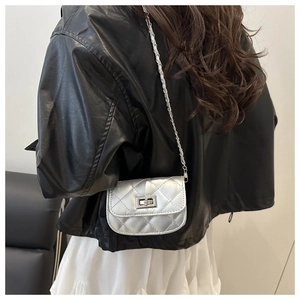 Gros plan du mini sac argenté matelassé avec chaîne en métal porté par un mannequin en été