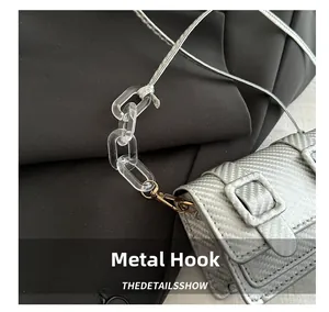Detail of silver textured square bag with golden hardware hook and acrylic chain
