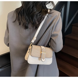 Detail of white leather and gold glitter crossbody bag worn with a gray blazer