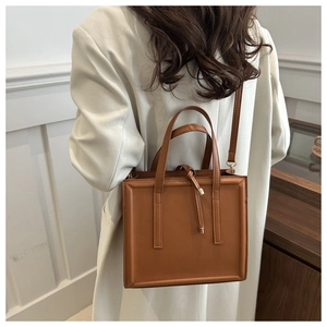 Brown rectangular shoulder bag featuring minimalist edge stitch design and handle details