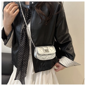 Détail du mini sac bandoulière argenté matelassé avec chaîne sur la tenue du mannequin