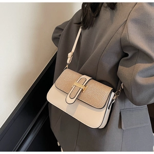 Detail of cream leather shoulder bag with woven flap texture and gold metal buckle