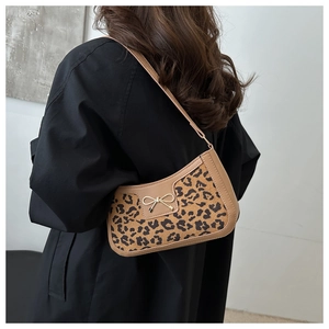 Detail of hobo shoulder bag with leopard print and golden bow buckle on model back