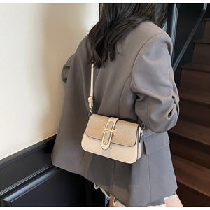 Detail of elegant shoulder bag with golden T-buckle and woven texture on stairs