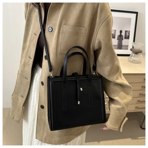 Minimalist black square tote bag in matte synthetic leather styled on model
