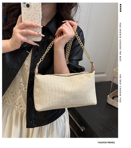 Détail du sac à main beige tressé avec bandoulière chaîne dorée et fermeture éclair