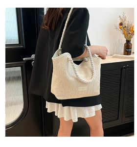 Elegant large woven straw tote bag for women shown in a stylish shoulder carrying view