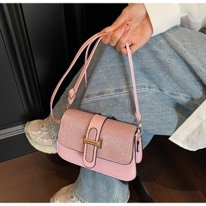 Close-up of pink sequined flap bag with gold H-shaped clasp and leather texture