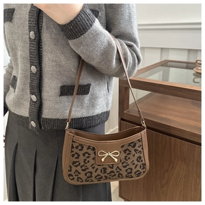 Close-up of stylish leopard print baguette bag featuring a golden bow metal buckle detail