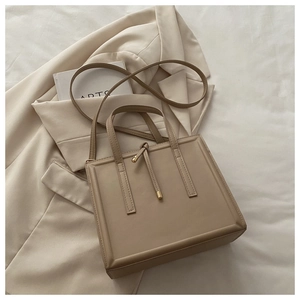 Detail of minimalist beige crossbody bag with knotted drawstring and gold metal accents