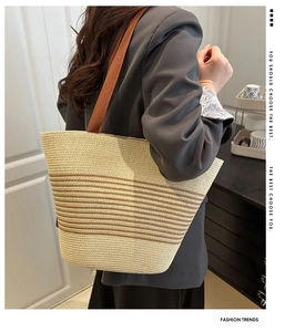 Detail of striped straw tote bag showing thick brown shoulder straps and woven texture