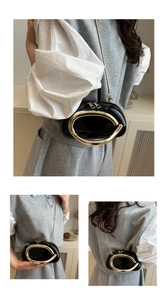Detail of black patent leather crossbody bag with iconic gold ring handle and chain strap
