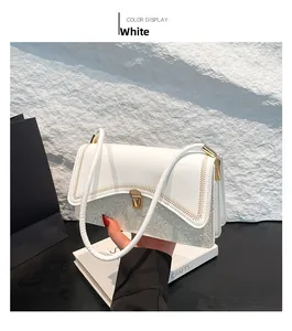 Close-up of white leather handbag with silver sequins and gold metal twist lock buckle