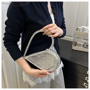 Close-up of silver teardrop evening bag featuring sparkling rhinestone handle and edges