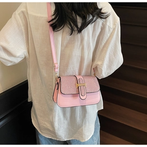 Detail of pink shoulder bag with glitter texture and gold H-buckle on female model