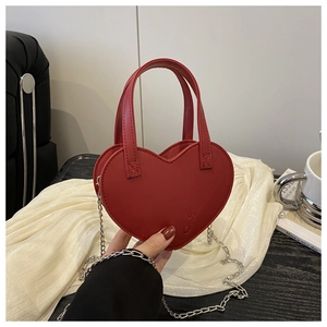 Détail du sac à main rouge en forme de cœur avec lettres embossées et bandoulière