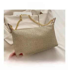 Détail du sac bandoulière en paille tressée crème avec chaîne dorée et texture