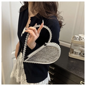Close-up of heart-shaped silver evening bag with sparkling rhinestone handle and texture